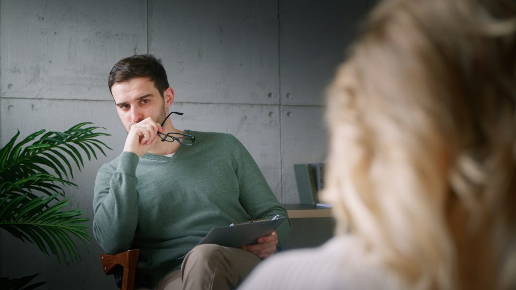 Young man with clipboard at psychotherapy in office